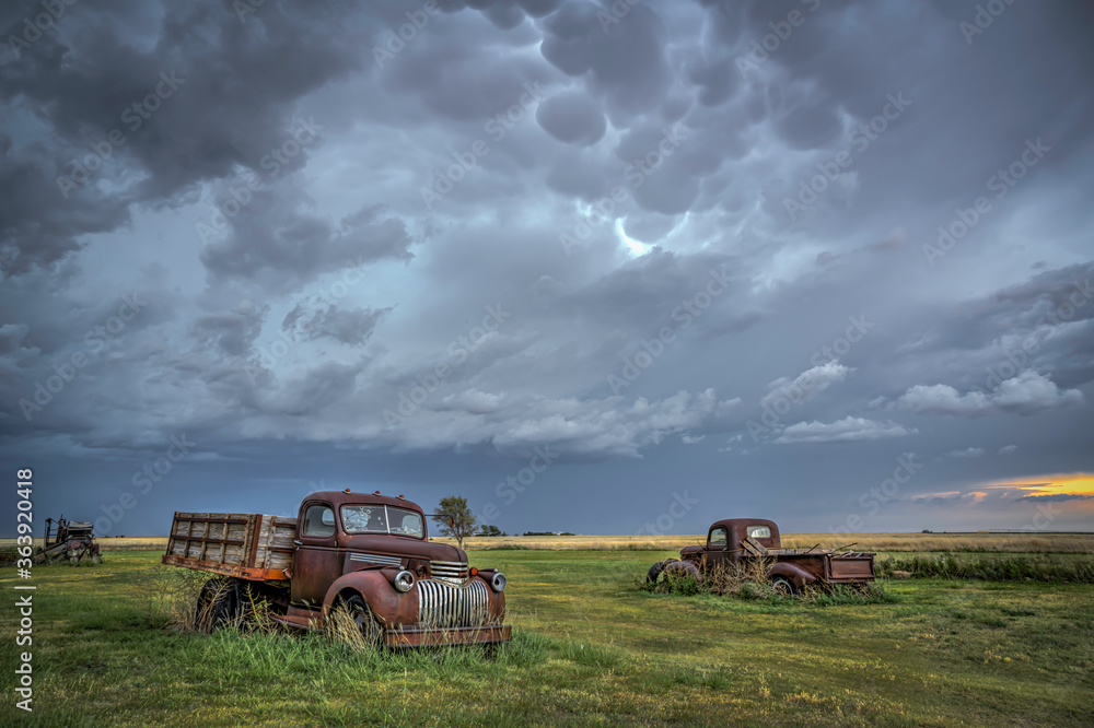 Obraz premium Old, abandoned vehicles on the Great Plains as Severe Weather Approaches