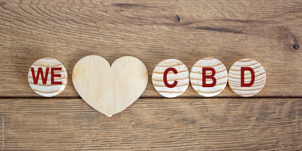 Concept words 'we' and 'cbd' on wooden circles. Wooden heart. Beautiful wooden background. Concept words 'we' and 'cbd' on wooden circles. Wooden heart. Beautiful wooden background.