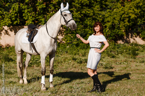 beautiful white horse with saddle and woman in white dress
