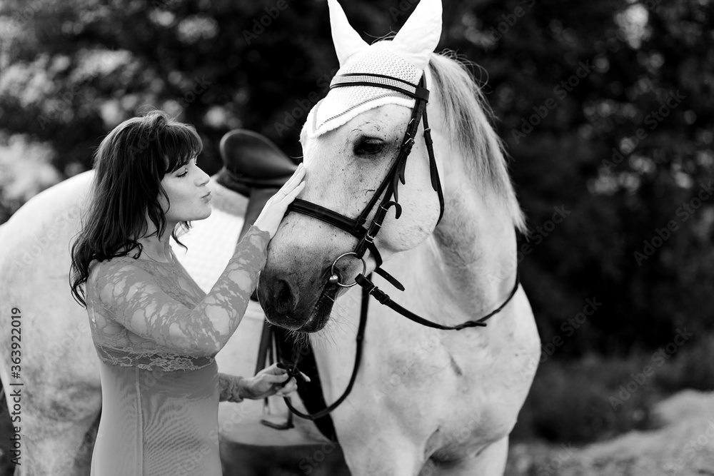 Obraz premium A woman kisses a beautiful white horse. black white photo