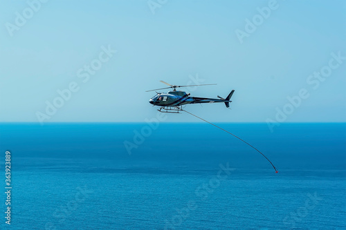 A maintenance helicopter repairing the  coastal path towards the Cinque Terre village of Corniglia in the summertime
