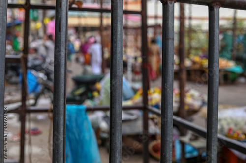 Blurred street vendor shop behind a metal prison bars background