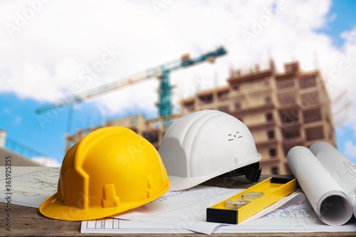 Blueprints and tools with hardhats on construction site