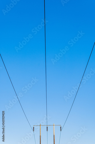 Electricity pylon cables against blue sky