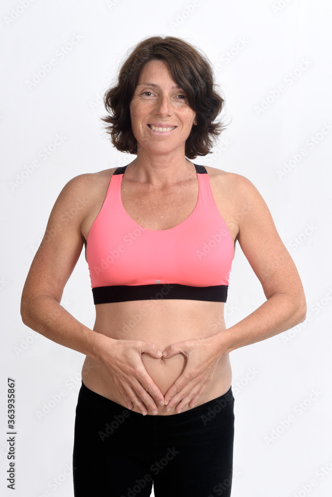 pregnant woman with sportswear and sign of heart on her belly isolated on white background,