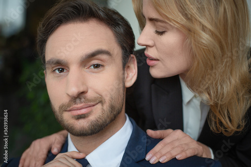 Woman stroking male shoulders. Passionate couple of two Caucasian business people. Close up portrait. Selective focus on male face. Flirt or love affair at job. © Svyatoslav Lypynskyy