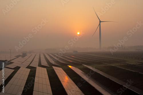 Wind power and solar power plants at sunrise and sunset
