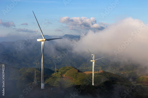 High in the mountains are wind turbines at sunrise and sunset and a sea of clouds