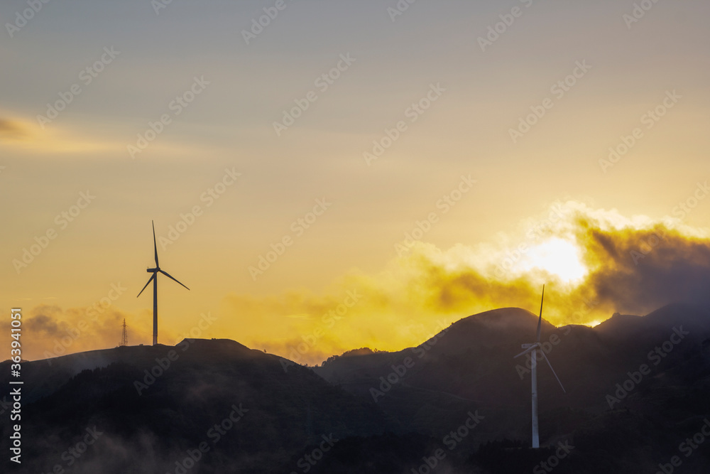 Obraz premium High in the mountains are wind turbines at sunrise and sunset and a sea of clouds