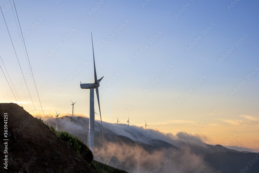 Obraz premium High in the mountains are wind turbines at sunrise and sunset and a sea of clouds