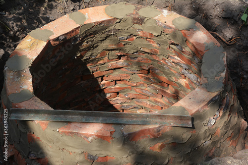 Building a round septic tank, sewer, sewage, cesspool or soak pit for domestic wastewater from red bricks for a private home. photo