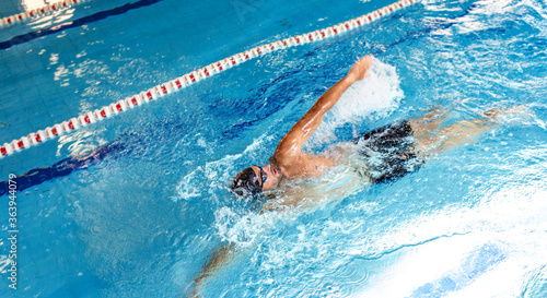 Man swimmer is swimming in the pool, backstroke technique swimming. Shot of swim in motion photo