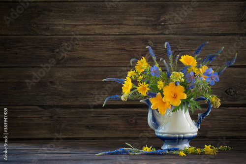 Wallpaper Mural bouquet with blue and yellow flowers in teapot on wooden table Torontodigital.ca