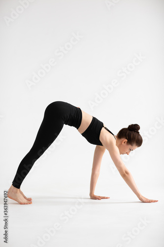 Sporty yoga girl on white background stretching in pose Adho Mukha Svanasana  downward-facing dog Pose  downward dog  down dog. Concept of healthy life and natural balance. Full length
