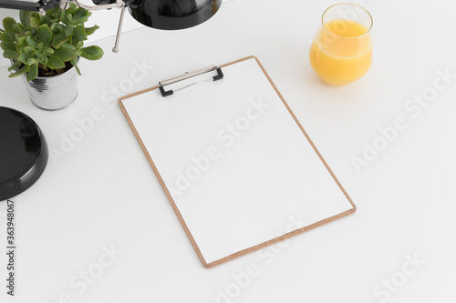 Wooden clipboard mockup wtih a succulent in a pot, lamp and a juice on a white table. © Snoflinga