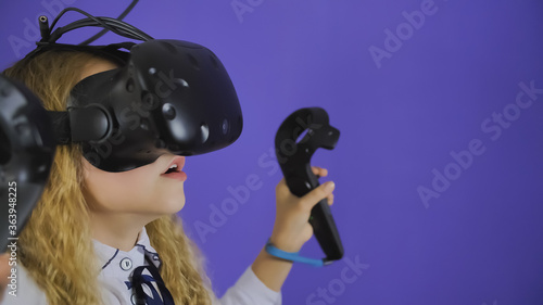 A teenage girl plays a virtual game in black virtual reality glasses. © Довидович Михаил