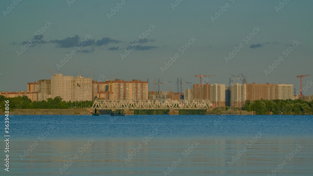 View of residential buildings in golden light on the Voronezh reservoir from the right bank in summer