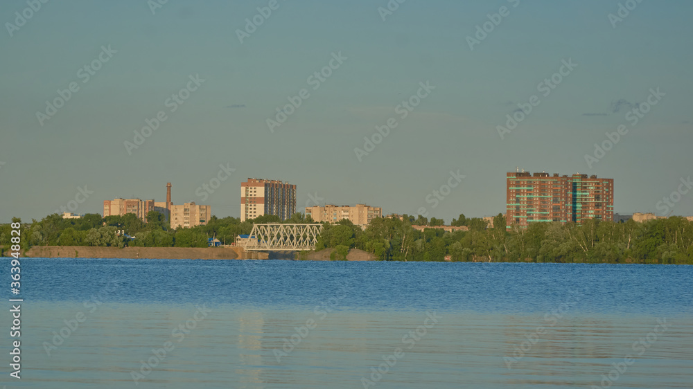 View of residential buildings in golden light on the Voronezh reservoir from the right bank in summer