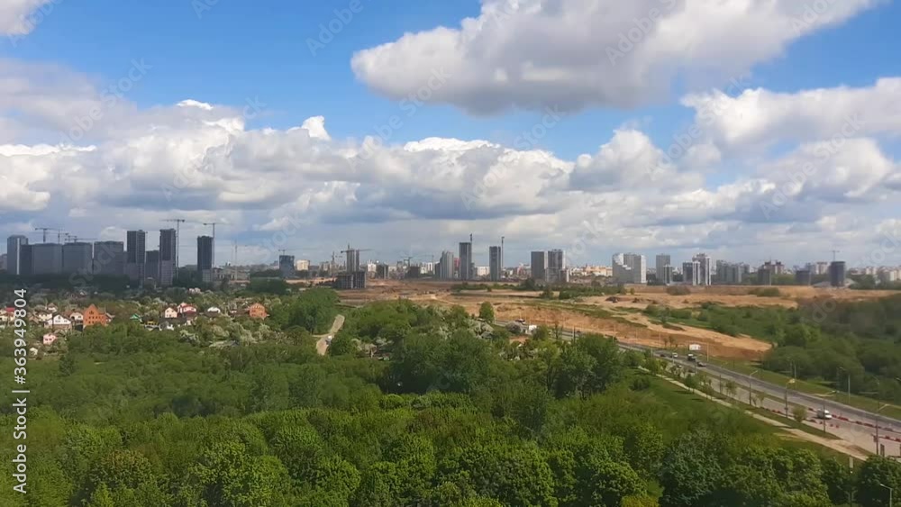 Timelaps video panorama of the city with parks from a height. Blue sky with clouds on buildings under construction. Timelaps video panorama of the city with parks from a height. Blue sky with clouds on buildings under construction.