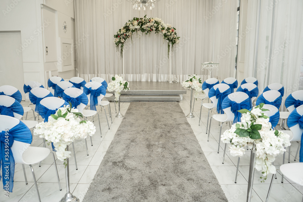 Bright room for weddings. Rows of guest chairs decorated with blue cloth Bright room for weddings. Rows of guest chairs decorated with blue cloth