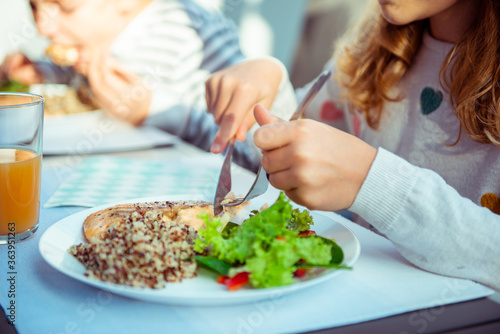 Photography Close up photo of hands of child girl eating healthy dinner with salad, quinoa a