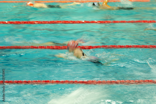 An abstract blur of a female swimmer doing the breast stroke during warmups at a swim meet. 