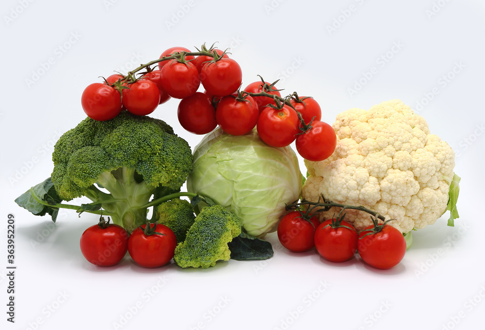 Head of cabbage, inflorescences of broccoli and cauliflower and red ripe tomatoes on a light background. Natural product. Natural hue. Close-up. Head of cabbage, inflorescences of broccoli and cauliflower and red ripe tomatoes on a light background. Natural product. Natural hue. Close-up.