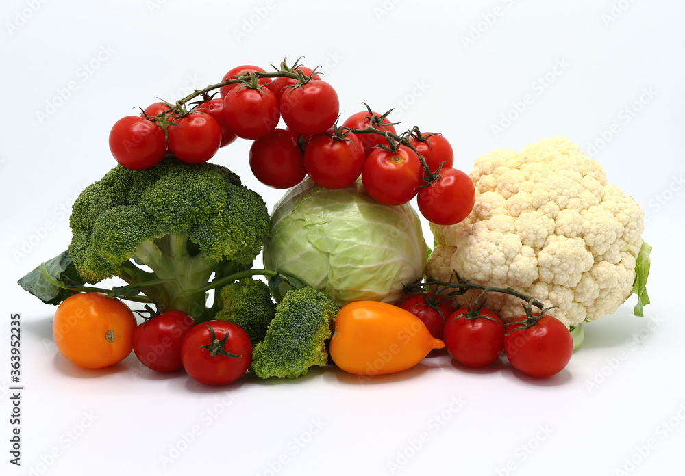 Head of cabbage, inflorescences of broccoli and cauliflower and red and yellow ripe tomatoes on a light background. Natural product. Natural hue. Close-up. Head of cabbage, inflorescences of broccoli and cauliflower and red and yellow ripe tomatoes on a light background. Natural product. Natural hue. Close-up.
