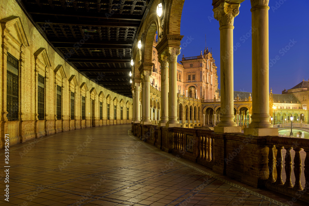 Spanish Square - A wide-angle dusk view of the illuminated ground-level portico curving along the semi-circular brick building at Spanish Square - Plaza de España, Seville. Andalusia, Spain.