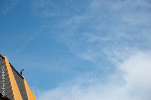 black spotlight install to top of yellow and black metal sheet building in right side with blue sky cloudy weather stock photo