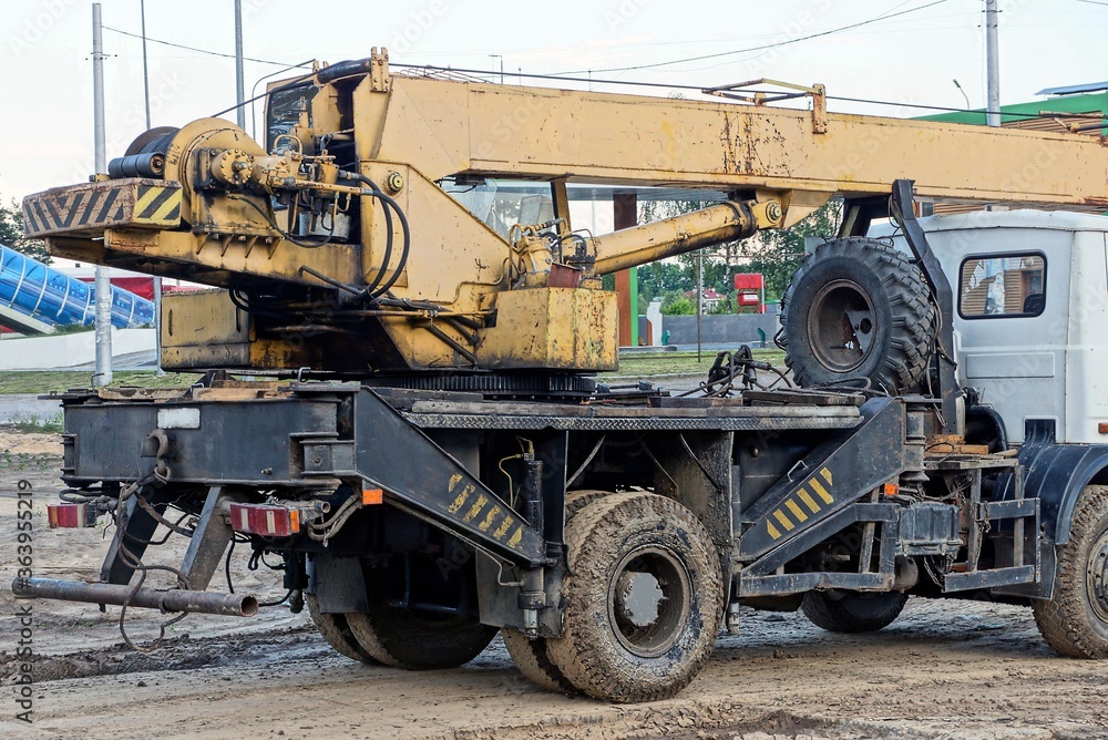 part of an industrial dirty car with a yellow iron crane on the street