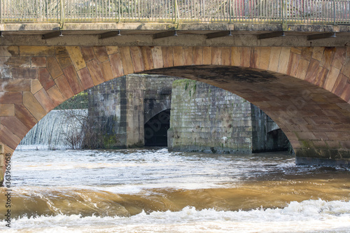 Water flowing under a stone arched bridge