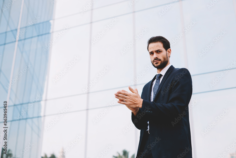 Handsome businessman in suit rubs his hands with premonition of profit, man with good feeling standing near office building Handsome businessman in suit rubs his hands with premonition of profit, man with good feeling standing near office building