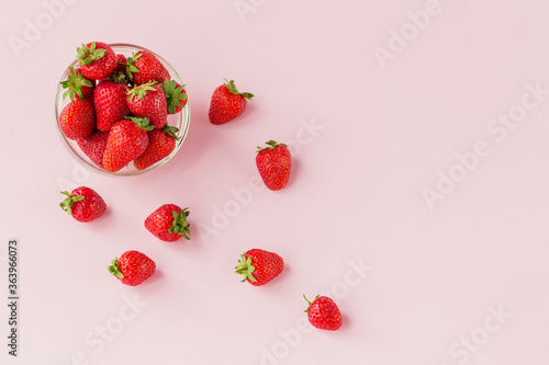 Fresh strawberries in transparent glass bowl top view. Healthy food on light pink table mockup. Delicious, sweet, juicy and ripe berry background