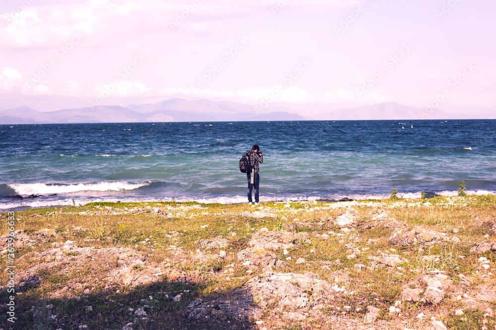 Traveller man by the lake near mountains