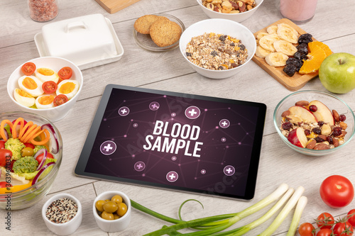 BLOOD SAMPLE concept in tablet pc with healthy food around, top view