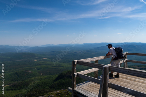 Hiker admiring the beautiful view from the top of the mont-du-lac-des-cygnes (Swan lake mountain) in Charlevoix, Quebec