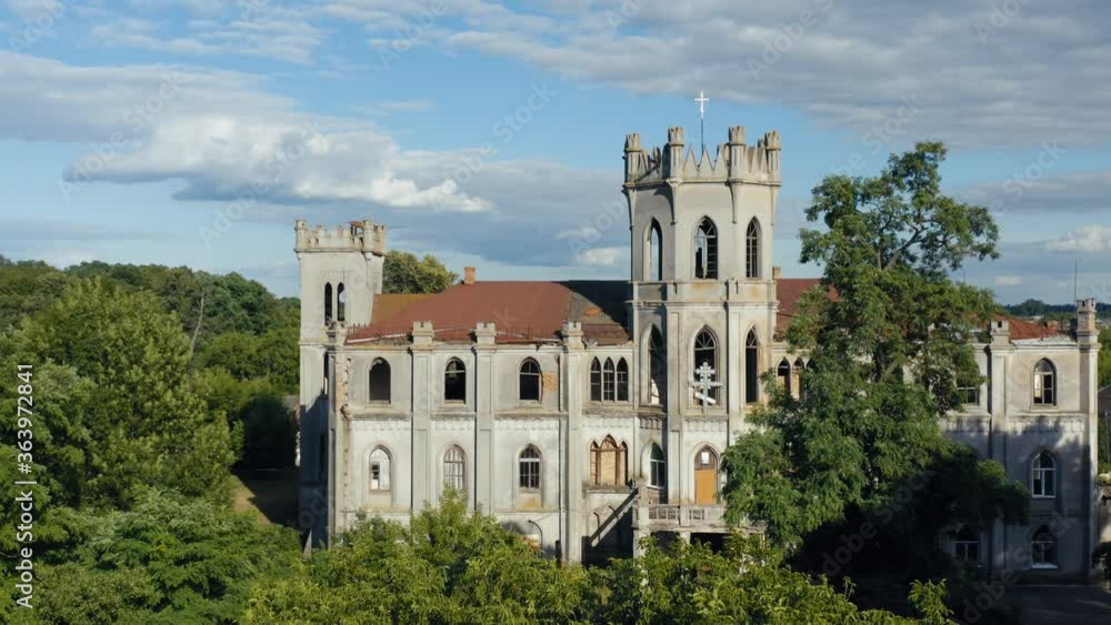Abandoned 19th century palace (manor or mansion house) with broken windows in Neo-Gothic (Gothic Revival) style. Aerial side view. Abandoned 19th century palace (manor or mansion house) with broken windows in Neo-Gothic (Gothic Revival) style. Aerial side view.