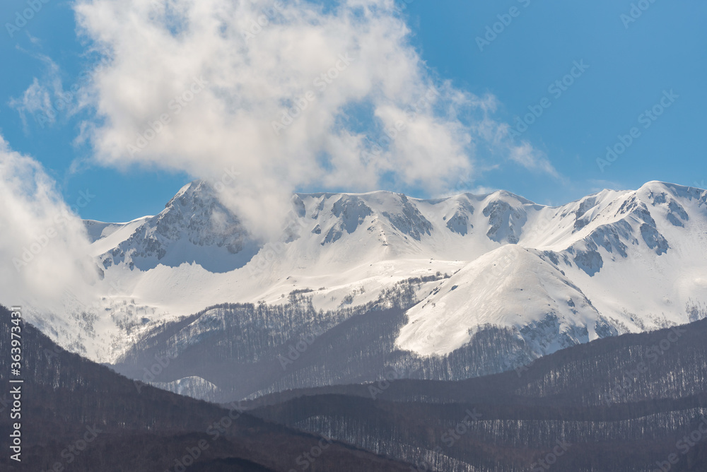 Mountain with snow and puffy clouds in Italy