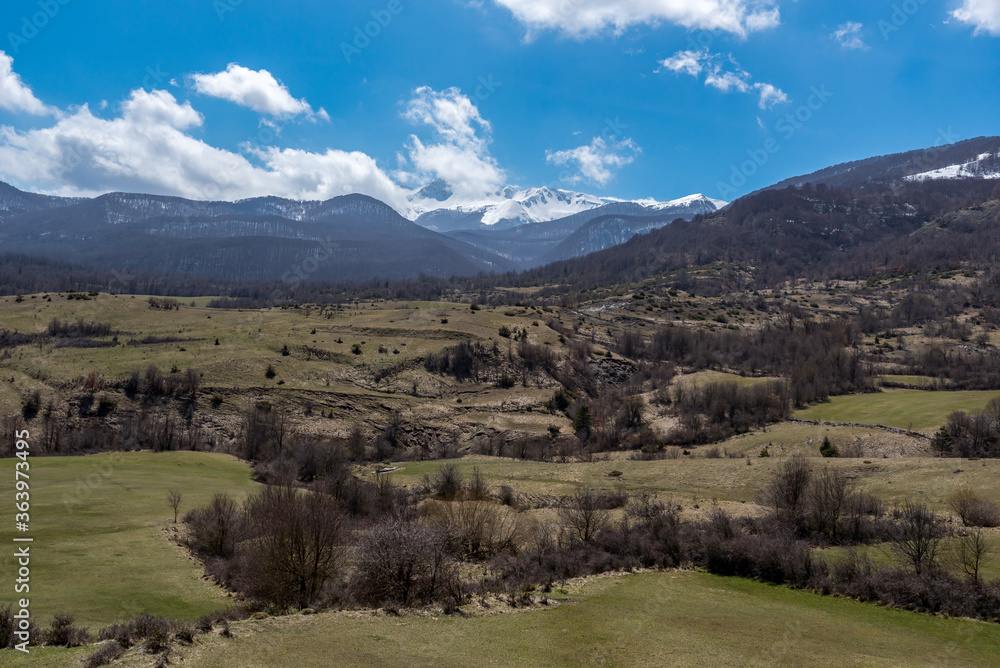 Landscape of green fields with mountains in the background and blue skies in the province of L'Aquila in the Abruzzo region of Italy.