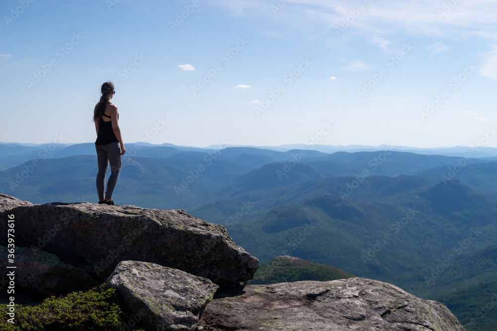 Back view of a young woman standing at the summit of the 