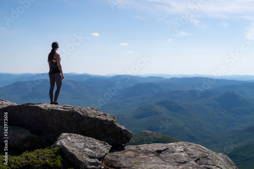 Back view of a young woman standing at the summit of the "Mont-du-lac-des-cygnes" in Charlevoix, Quebec