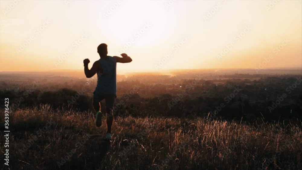 The young sportsman runs on the top of the hill with beautiful view. slow motion The young sportsman runs on the top of the hill with beautiful view. slow motion