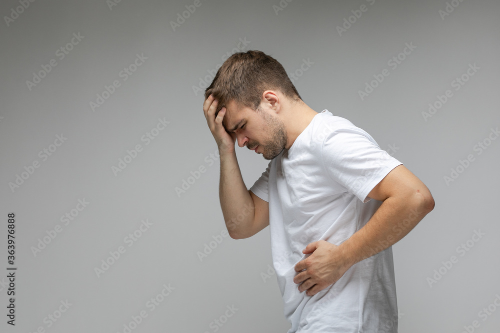 The young guy has severe abdominal pain. Guy holds his stomach