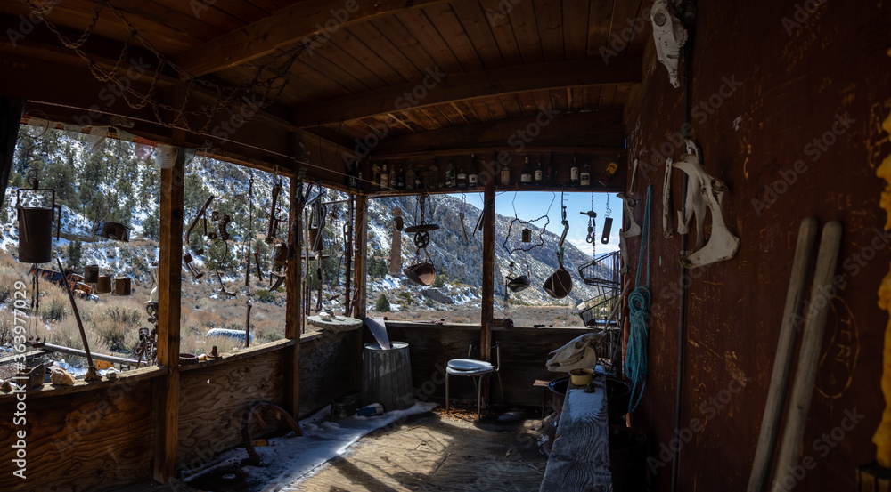 A view from the cabin porch on an abandoned miner's cabin in the Panamint City ghost town in Death Valley National Park, California. Eclectic wind chimes are seen hanging from the cabin.