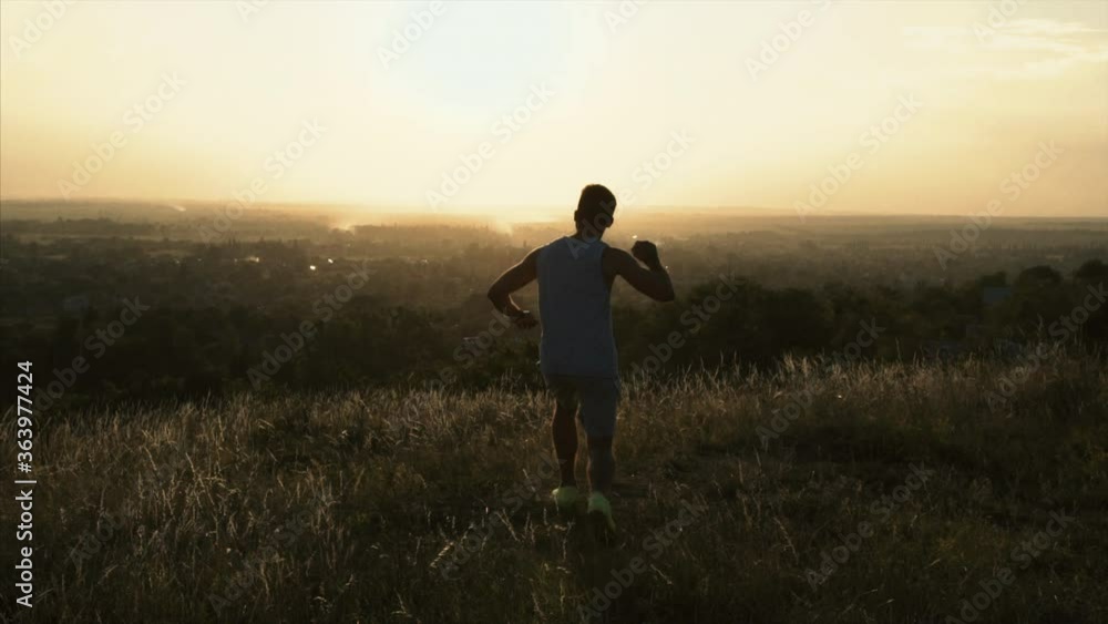 The young sportsman runs on the top of the hill with beautiful view. slow motion The young sportsman runs on the top of the hill with beautiful view. slow motion