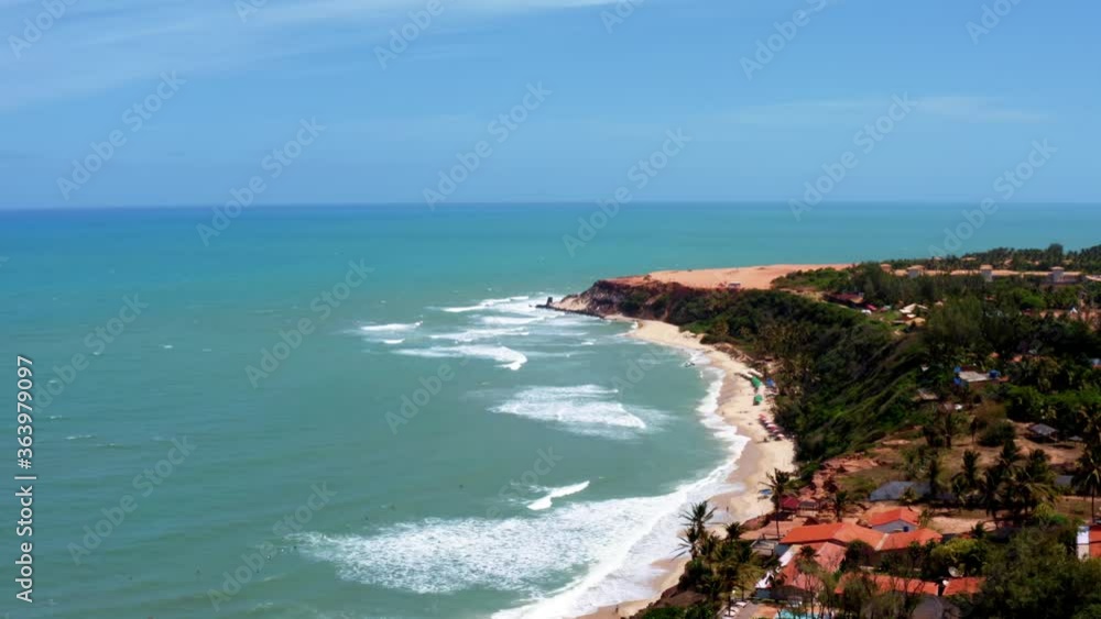 Beautiful aerial drone shot of the tropical coastline of Northern Brazil from the famous beach Praia do Amor with blue water, orange sand cliffs, tourists and surfers below Beautiful aerial drone shot of the tropical coastline of Northern Brazil from the famous beach Praia do Amor with blue water, orange sand cliffs, tourists and surfers below