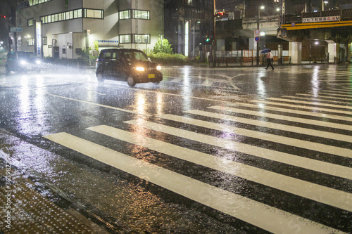 Vászonkép Small car crosses intersection in heavy rain at night