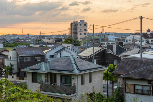 Solar panels top many roofs in typical Japanese residential neighborhood at sunset