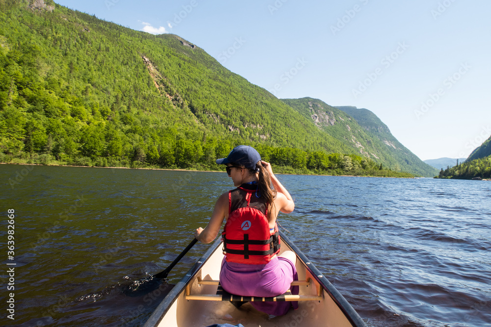 Back view of a young woman canoeing on the Malbaie river in Canada